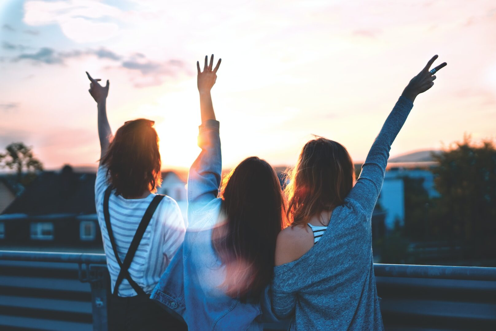 Three women standing next to each other with their arms raised.