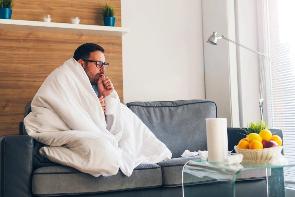 A man wrapped in a blanket sitting on top of a couch.